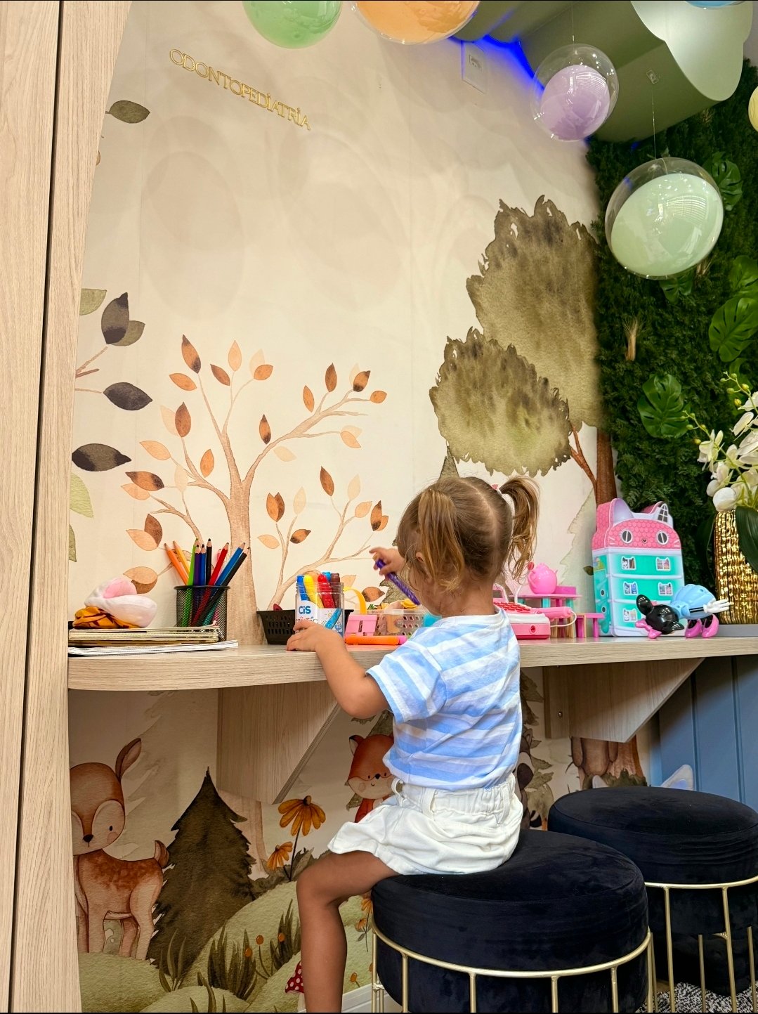 Espaço infantil do consultório com brinquedos e decoração de floresta